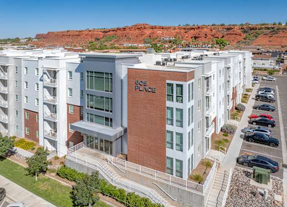 A modern apartment complex with a red brick building in the center. 605 Place Student Housing & Co-Living, St George, UT