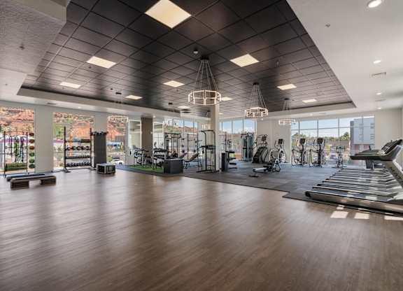 a gym with treadmills and other exercise equipment and windows at 605 Place Student Housing & Co-Living, St George, UT, 84770