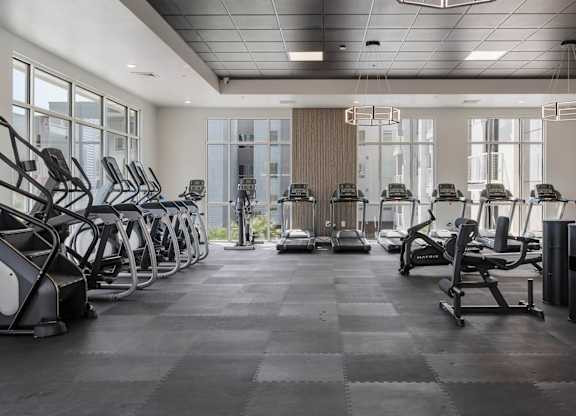 a large fitness room with cardio equipment and windows at 605 Place Student Housing & Co-Living, St George, UT