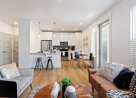 a living room and kitchen area with white walls and hardwood floors at Alante Homes at Lake Hazel, Boise, ID, 83709