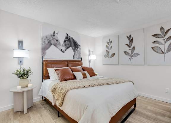 a bedroom with a bed and paintings of horses at AVIA Lofts on Liberty Ridge Apartments, Jacksonville