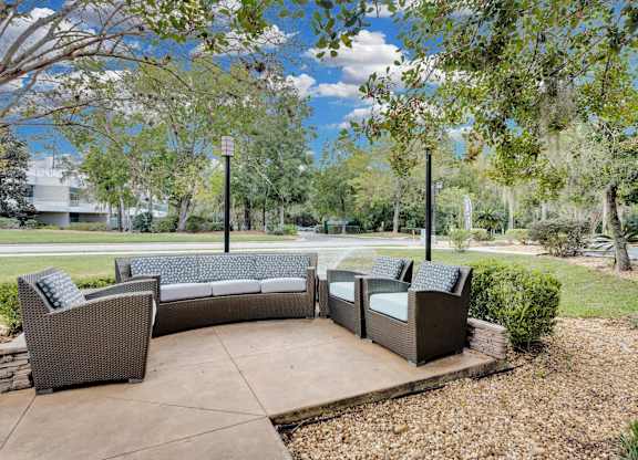 a patio with couches and chairs and trees at AVIA Lofts on Liberty Ridge Apartments, Florida, 32256