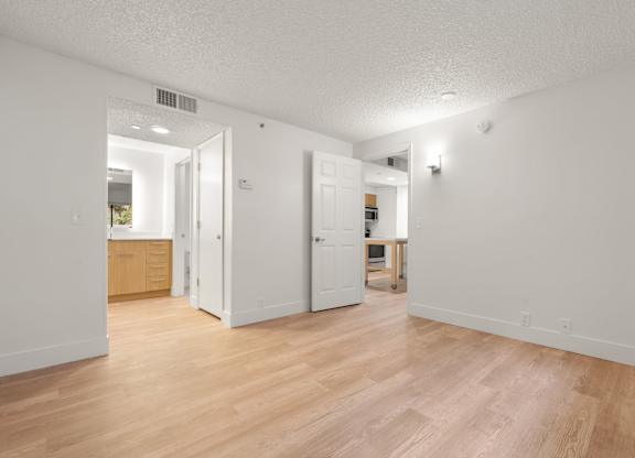 a living room and kitchen with wood flooring and white walls at AVIA Lofts on Parkway Apartments, Washington