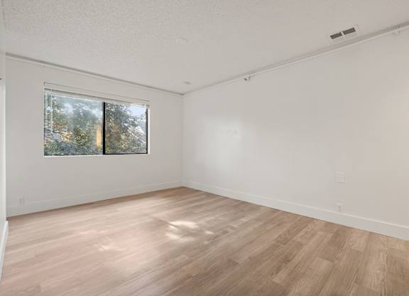 a spacious living room with wood floors and a window at AVIA Lofts on Parkway Apartments, Vancouver, WA