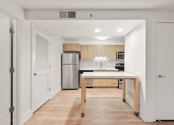 a kitchen with a large island and a stainless steel refrigerator at AVIA Lofts on Parkway Apartments, Washington, 98662