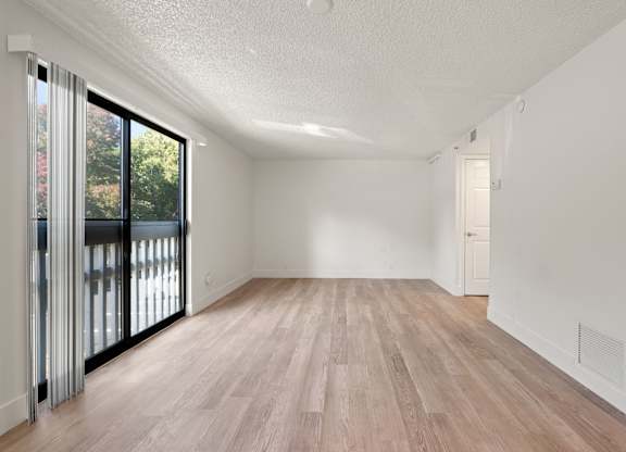 an empty living room with a sliding glass door to a balcony at AVIA Lofts on Parkway Apartments, Vancouver, Washington