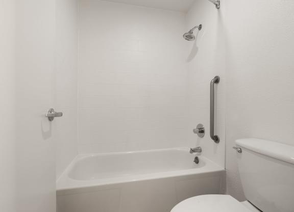 a white bathroom with a tub and a toilet at AVIA Lofts on Parkway Apartments, Washington, 98662