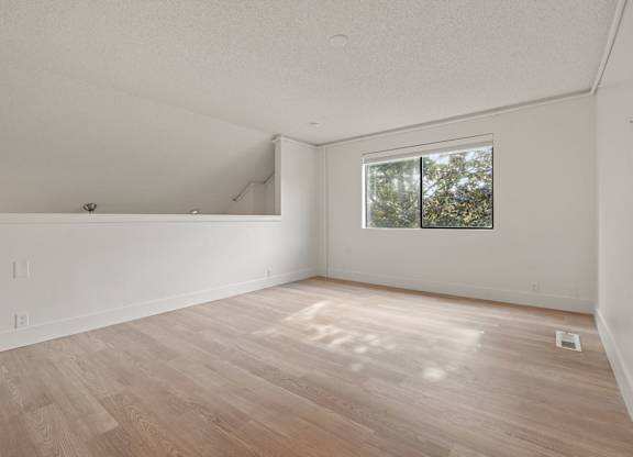 the living room of an empty house with wood floors and a window at AVIA Lofts on Parkway Apartments, Vancouver, WA, 98662