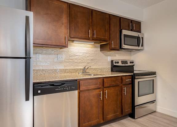 Kitchen with wooden cabinets and stainless steel appliances at AVIA Lofts on Victors Way, Ann Arbor, MI, 48108