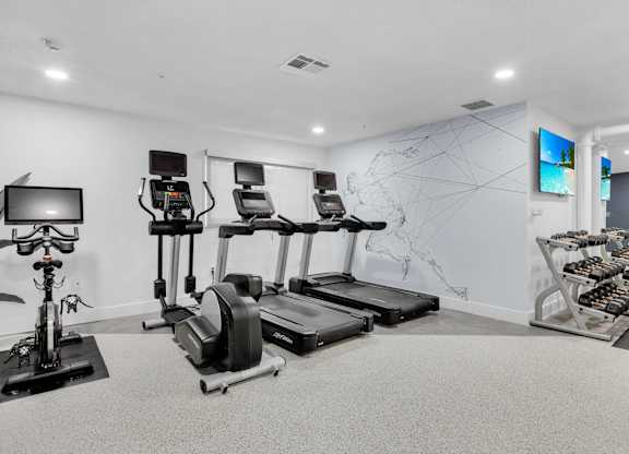 the gym with treadmills and weights and a map on the wall at AVIA Lofts on Liberty Ridge Apartments, Florida, 32256