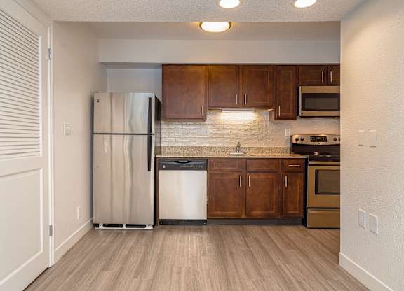 Kitchen with wooden cabinets and stainless steel appliances at AVIA Lofts on Victors Way, Ann Arbor, 48108