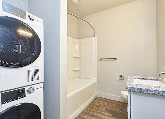 A white washing machine and dryer in a small bathroom at Brickside Heights Apartments, Millcreek