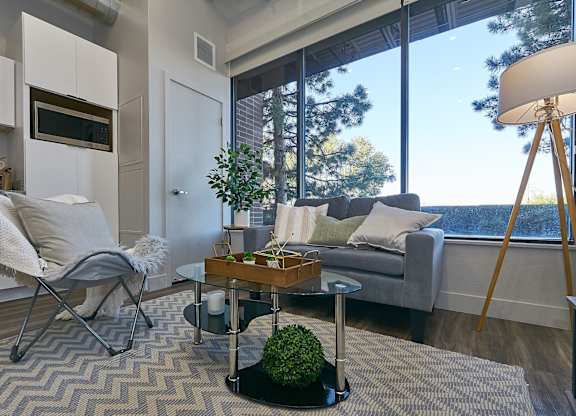 A modern living room with a grey couch, a white chair, and a wooden coffee table. at Brickside Heights Apartments, Apartments, Millcreek, UT