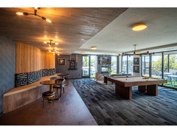 A room with a pool table and a bar area.