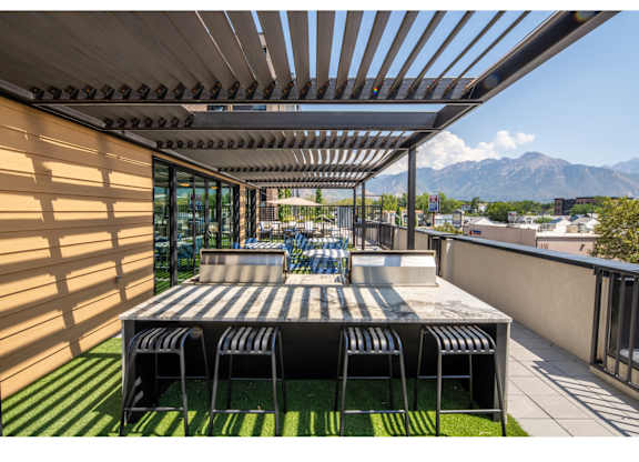 A patio with a table and chairs overlooking a mountain range.
