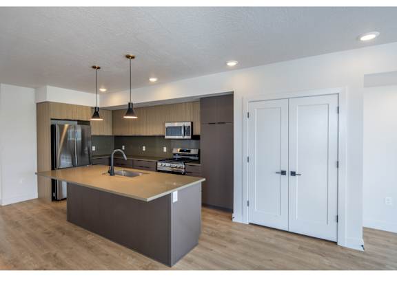 A modern kitchen with a sink, stove, and refrigerator.
