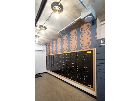 A wall of black lockers with a blue and orange patterned wall behind them.