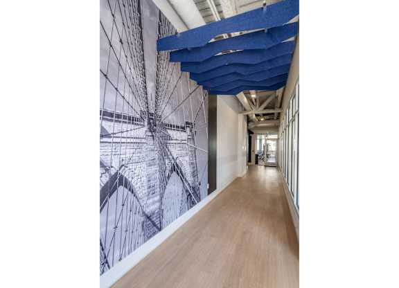 A long hallway with a blue ceiling and a wall with a black and white drawing on it.