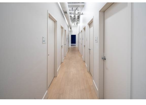 A long hallway with doors on both sides and a blue door at the end.