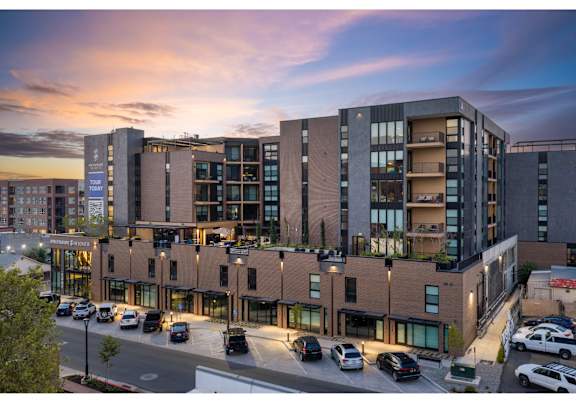 A modern multi-story building with a parking lot in front.