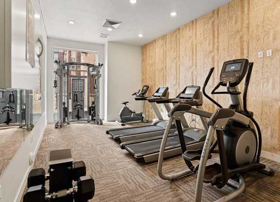 a gym with treadmills and other exercise equipment on a wooden wall at 200 City View, Provo