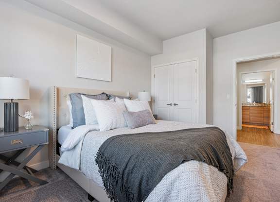 a bedroom with a large bed and a door to a bathroom at The Flats at Riverwoods, Provo, Utah