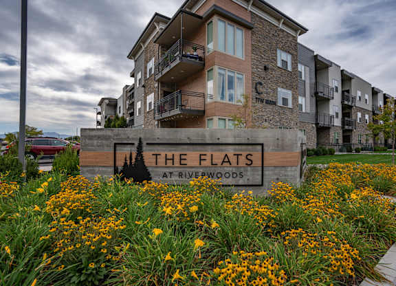 apartments sign in front of grass and flowers at The Flats at Riverwoods, Provo, Utah