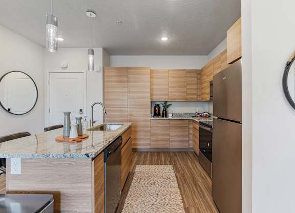 a kitchen with wooden cabinets and stainless steel appliances at The Flats at Riverwoods, Provo, Utah