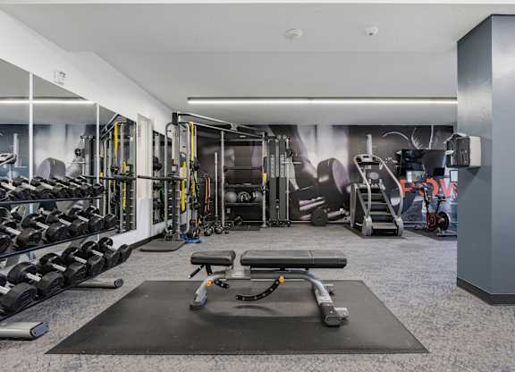 a gym with weights and cardio equipment on the floor and a wall with a mural at The Flats at Riverwoods, Provo, UT, 84604