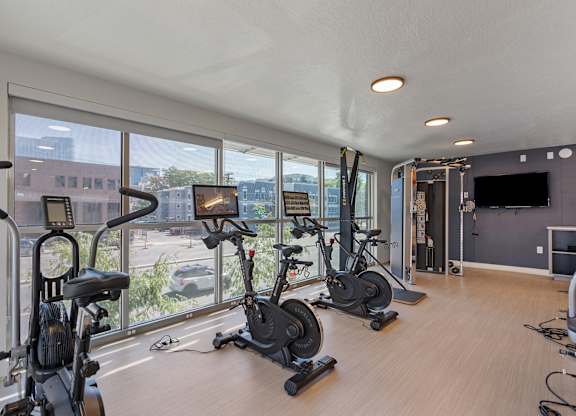 A spacious room with a row of stationary bikes and a television.
