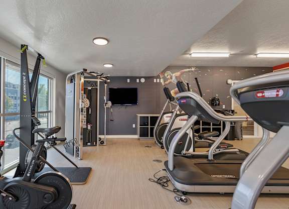 A gym with treadmills, exercise bikes and a television.