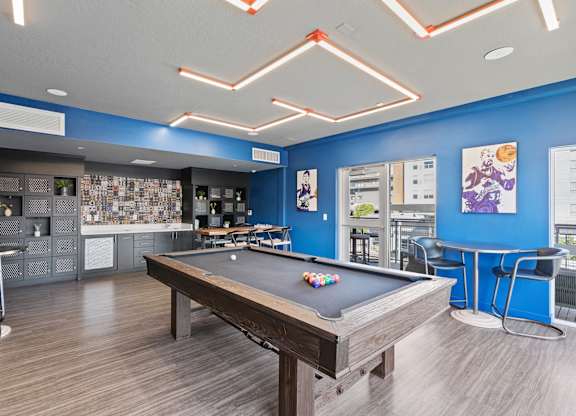 A pool table is in the middle of a room with a blue wall.
