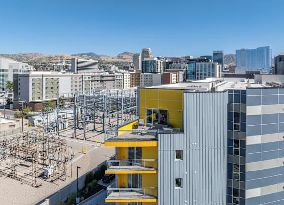 A modern building with a yellow section in the middle is in the foreground of a cityscape.