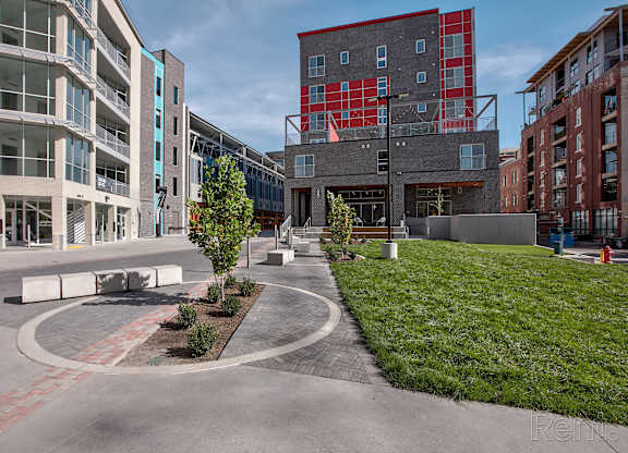 A modern courtyard surrounded by buildings with a tree and benches.