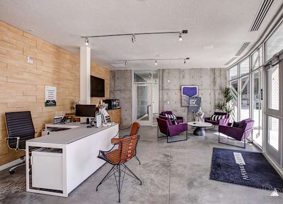 A modern office space with a white desk, purple chairs, and a wooden wall.