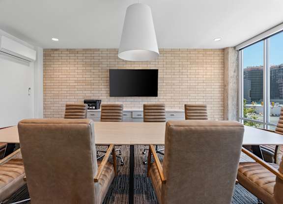a conference room with a table and chairs and a tv on the wall at The Revival, Salt Lake City, UT, 84101