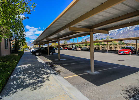 A parking lot with cars parked under a covered area. at Siena Villas Apartments, Orem, 84097