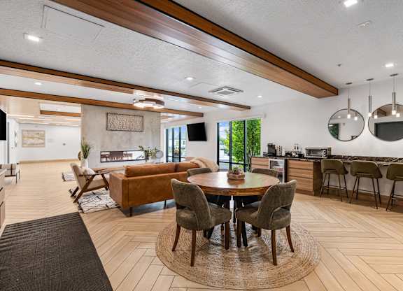 a living room with a table and chairs and a kitchen at The Flats at Riverwoods, Provo