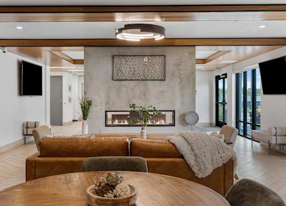 a living room with a couch and a table and a fireplace at The Flats at Riverwoods, Provo, UT, 84604