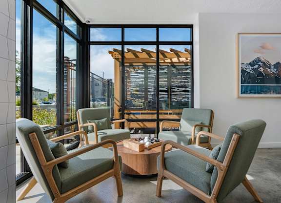 a living room with chairs and a coffee table and a view of a mountain at The Flats at Riverwoods, Provo