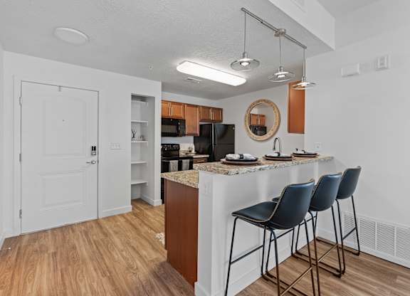 a kitchen with bar stools and a breakfast bar with three stoolsat The View on 20th, Ogden, UT