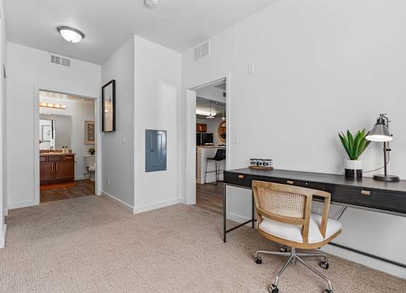 an office space with a desk and a chair and a doorway to a bathroomat The View on 20th, Ogden