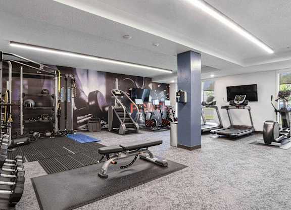 a spacious fitness room with cardio equipment and a flat screen tv at The Flats at Riverwoods, Utah, 84604