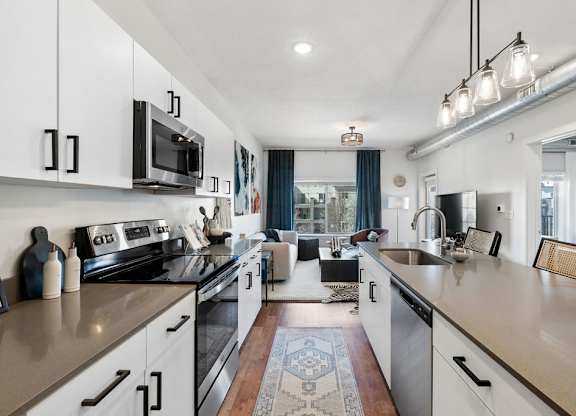 an open kitchen with counters and appliances and a living room at The Revival, Salt Lake City, 84101