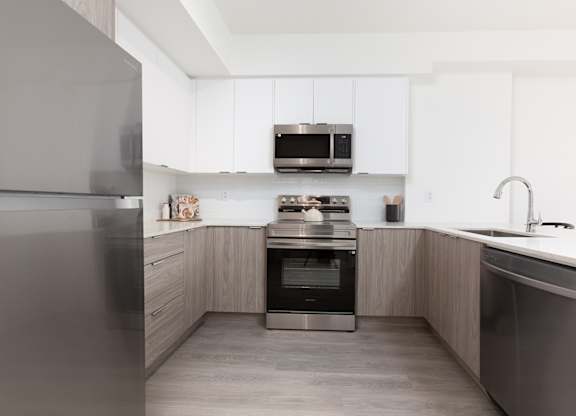 A modern kitchen with a refrigerator, oven, and sink.