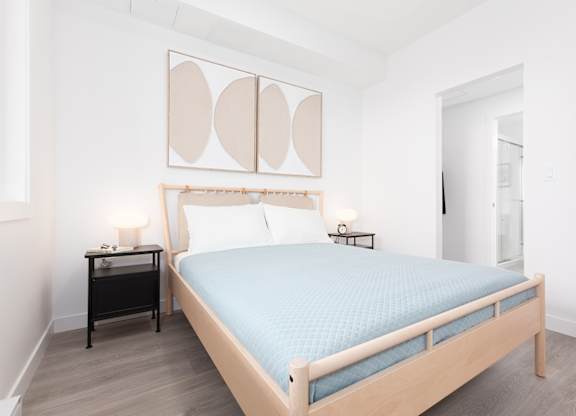 A bedroom with a bed, nightstand, and lamp.