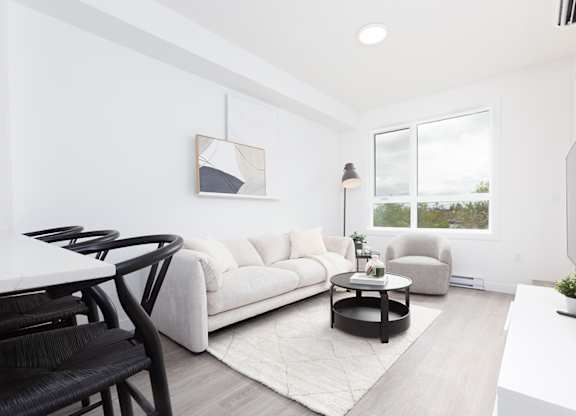 A modern living room with a white couch, a coffee table, and a television.