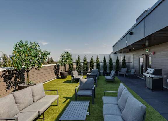 A patio with grey couches and a grill.