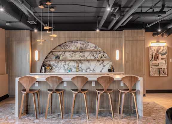 A bar with wooden stools and a marble backdrop.