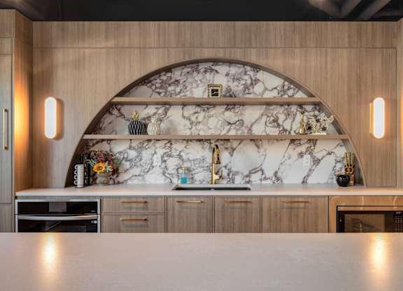 A kitchen with a marble backsplash and wooden cabinets.